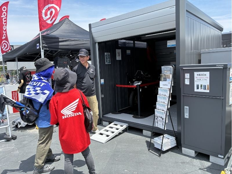 熱意あるスタッフが笑顔でお客様にバイクガレージのご案内をしている様子