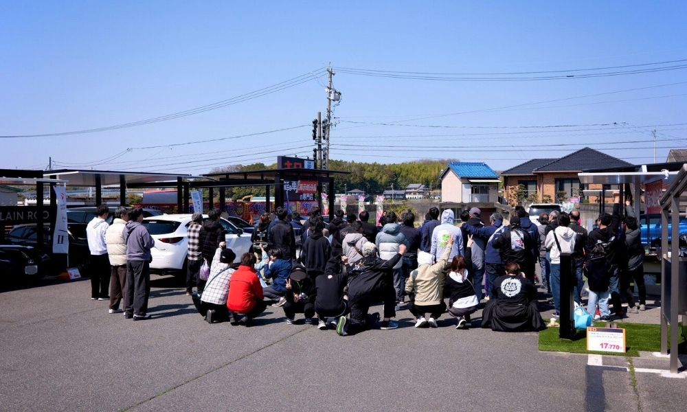 キロ夏焼店で開催された洗車マルシェの開会式の様子。大勢の参加者が集まっています。